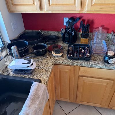 Assorted kitchenware including non-stick pots and pans, a knife block set, flatware in an organizer, glass baking dishes, and various...