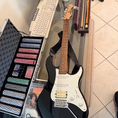 Sale Photo Thumbnail #286: Yamaha Pacifica electric guitar in black and white, displayed alongside a poker chip set in an aluminum case and pool cues.