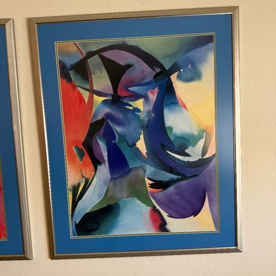Sale Photo Thumbnail #318: Framed abstract watercolor print featuring fluid shapes in blue, purple, and red, mounted with a blue mat in a silver-toned frame.