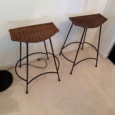 Sale Photo Thumbnail #300: Pair of contemporary bar stools featuring woven wicker saddle seats on dark metal frames with curved footrests.