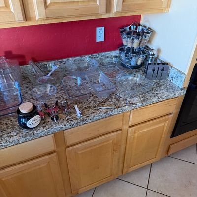 Assorted kitchenware including Pyrex baking dishes, glass mixing bowls, a rotating spice rack, and various bar tools displayed on a...