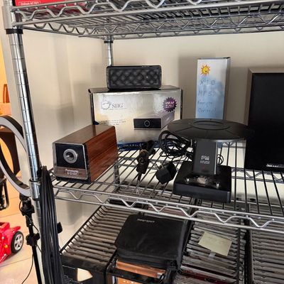 Assorted electronics on wire shelving, including a vintage Panasonic woodgrain pencil sharpener, an FM antenna, and various boxed...