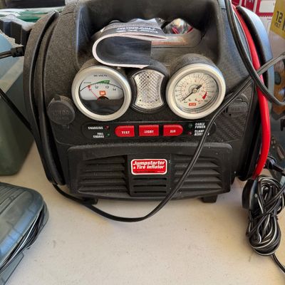 PowerStation jumpstarter and tire inflator unit featuring dual analog gauges, integrated light, and red control buttons.