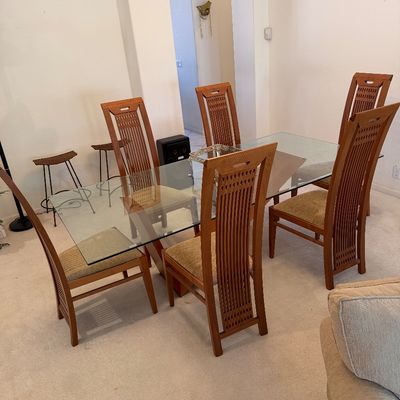 Sale Photo Thumbnail #307: Contemporary dining set featuring a rectangular glass-top table on a wooden base, paired with six high-back wooden chairs with upholstered seats.