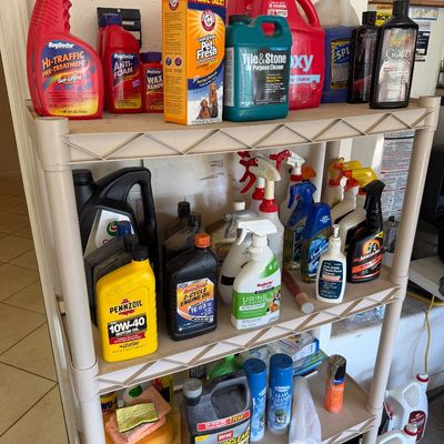 Four-tier plastic shelving unit holding an assortment of household cleaning supplies, automotive fluids, and pet care products.