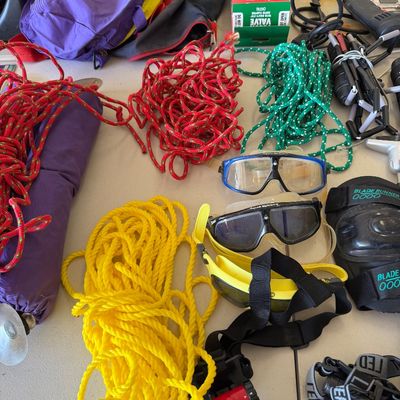 Assortment of outdoor and utility gear, including colorful nylon ropes, swim goggles, headlamps, and protective pads.