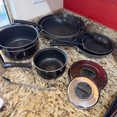 Sale Photo Thumbnail #220: Assorted non-stick cookware set including pots, pans, lids, and a pair of metal tongs, showing some signs of use.