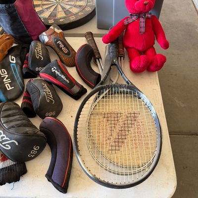 Assorted sporting goods including Wilson tennis rackets, various golf club headcovers from Titleist, Ping, and TaylorMade, a dartboard,...