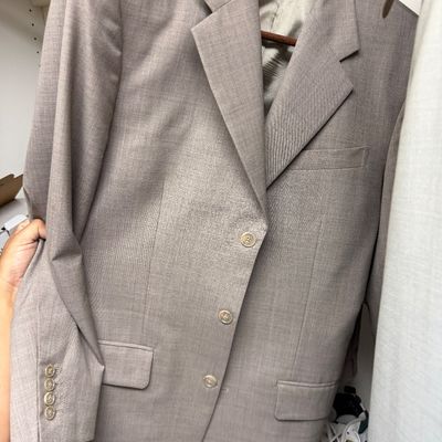 Sale Photo Thumbnail #114: Men's light brown or taupe three-button suit jacket with notched lapels and flap pockets, hanging in a closet.