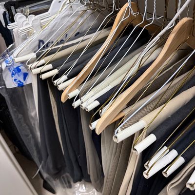 Sale Photo Thumbnail #118: Assortment of men's dress trousers and slacks in neutral tones, hanging on a closet rod.