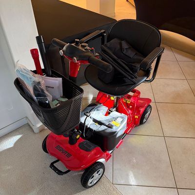 Eskate red four-wheel mobility scooter, featuring a black vinyl seat, front wire basket, and included accessories.