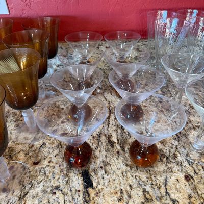 Sale Photo Thumbnail #212: Assorted vintage glassware, including amber-colored goblets, clear martini glasses with amber bubble bases, and clear textured tumblers.