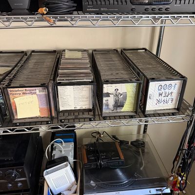 Assorted vintage audio equipment and media, including a Hitachi turntable, AudioSource graphic equalizer, and multiple racks of compact...