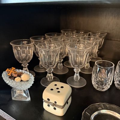 Sale Photo Thumbnail #188: Collection of vintage stemmed cordial glasses with paneled bowls, displayed alongside a ceramic dice-shaped trinket box and small cut-glass vessels.
