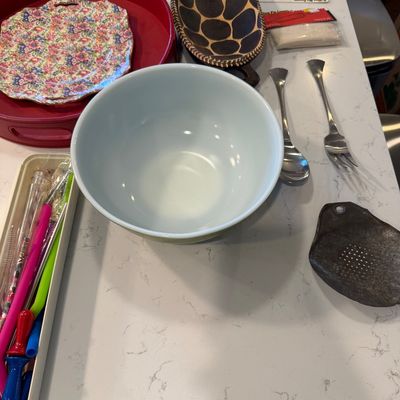 Sale Photo Thumbnail #124: Vintage Pyrex mixing bowl in light blue, displayed alongside a floral plate, red serving tray, and various kitchen utensils.