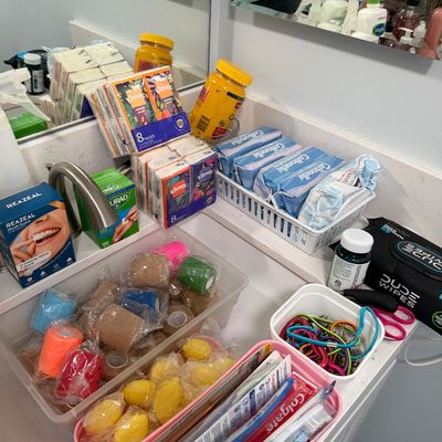 Sale Photo Thumbnail #85: Assortment of personal care and first aid items, including bandages, toothbrushes, wipes, and tissues, arranged on a bathroom counter.