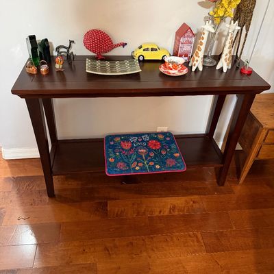 Sale Photo Thumbnail #73: Dark wood console table with a lower shelf, styled with various decorative items including giraffe figurines, a yellow model car, and framed artwork hanging above.