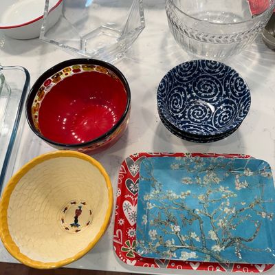 Sale Photo Thumbnail #122: Assorted kitchenware including a Vincent van Gogh "Almond Blossoms" tray, a yellow textured ceramic bowl, a red-interior decorative bowl, blue and white patterned bowls, and various clear glass serving bowls.