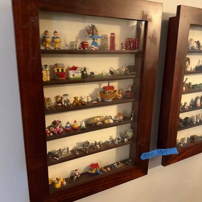 Sale Photo Thumbnail #29: Two wall-mounted wooden shadow boxes with glass fronts, displaying a large collection of miniature figurines, toys, and knick-knacks.