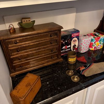 Sale Photo Thumbnail #31: Vintage wooden miniature chest of drawers alongside various collectibles, including boxed bobbleheads, a small wooden box, and decorative items on a dark countertop.