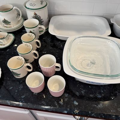 Sale Photo Thumbnail #135: Assorted vintage kitchenware, including Spode Christmas Tree mugs, a cookie jar, and pitcher, alongside CorningWare casserole dishes and pink patterned mugs.