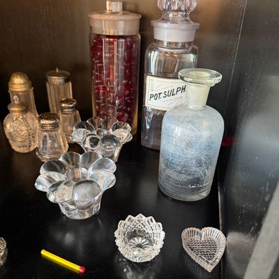 Sale Photo Thumbnail #179: Collection of vintage glassware, including apothecary bottles, salt and pepper shakers, and small decorative glass dishes.