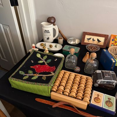 Sale Photo Thumbnail #26: Assortment of vintage collectibles including a wooden foot massager roller, a handmade fabric box with a bird motif, glass decanters, and a Black & White Scotch Whisky pitcher.