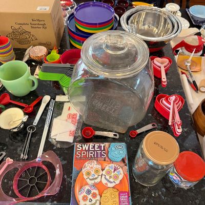 Sale Photo Thumbnail #145: Assorted kitchenware and baking supplies, including a large glass cookie jar, colorful mixing bowls, measuring cups, and a "Sweet Spirits" cookie cutter set.