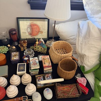 Sale Photo Thumbnail #20: Assortment of vintage collectibles and home decor, including woven baskets, miniature Capitol building replicas, playing cards, a framed anatomical eye diagram, and a small table lamp.