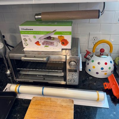 Sale Photo Thumbnail #120: Breville stainless steel toaster oven, a boxed Freshware vegetable chopper, a colorful polka dot Shangzher tea kettle, and other kitchen accessories on a countertop.