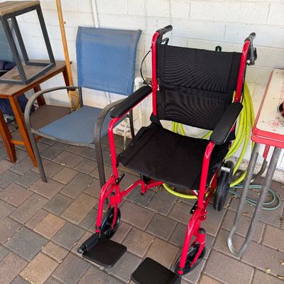 Sale Photo Thumbnail #167: Modern lightweight transport wheelchair featuring a bright red frame, black nylon seat and backrest, and swing-away footrests.
