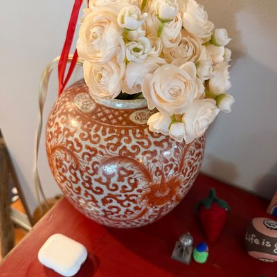 Sale Photo Thumbnail #74: Vintage Asian-style ceramic ginger jar vase featuring an intricate orange and white scrollwork pattern, filled with faux white roses.