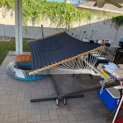 Sale Photo Thumbnail #163: Quilted navy blue hammock with wooden spreader bars, mounted on a black metal stand with wheels.