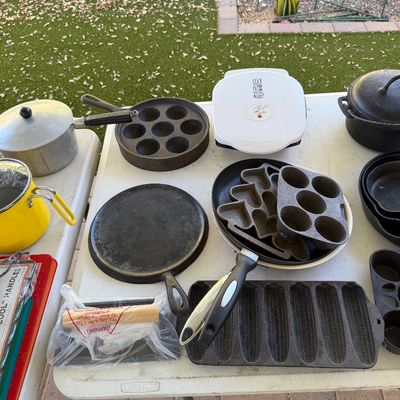 Sale Photo Thumbnail #157: Assortment of vintage cast iron cookware, including a griddle, corn stick pan, muffin pans, and skillets, displayed alongside a George Foreman grill and aluminum pots.