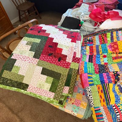 Sale Photo Thumbnail #10: Two handmade quilts, featuring a red and green log cabin pattern quilt and a vibrant, multi-colored patchwork quilt.
