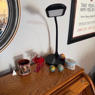Sale Photo Thumbnail #4: Modern black gooseneck LED desk lamp with touch controls, displayed alongside small decorative items including a miniature drum, red metal moose bookends, and small globes on a wooden roll-top desk.