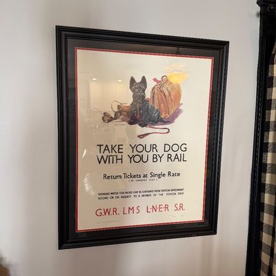 Sale Photo Thumbnail #203: Framed vintage-style British railway advertising poster featuring a Scottish Terrier, titled "Take Your Dog With You By Rail," presented in a black frame with a red inner mat.