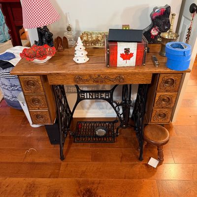 Sale Photo Thumbnail #5: Vintage Singer treadle sewing machine base repurposed as a vanity or desk, featuring ornate cast iron legs and a wooden top with six carved drawers.