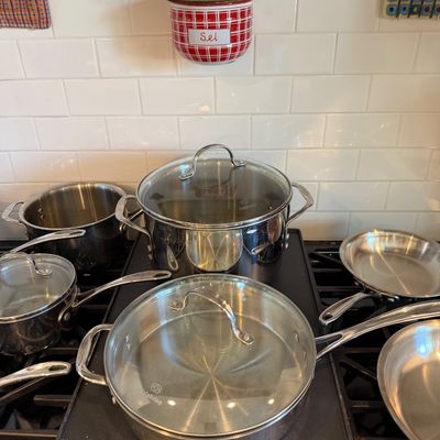 Sale Photo Thumbnail #117: Calphalon stainless steel cookware set, including pots and pans with glass lids, displayed on a stovetop.