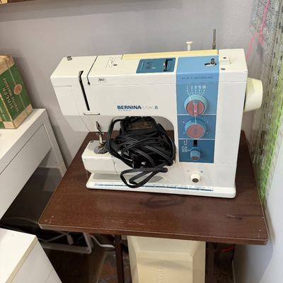 Sale Photo Thumbnail #36: Vintage Bernina Bernette 330 sewing machine with foot pedal, mounted on a wooden sewing table.