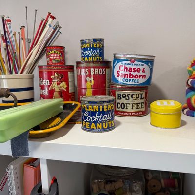 Sale Photo Thumbnail #43: Collection of vintage advertising tins, including Planters Cocktail Peanuts, Hills Bros Coffee, and Chase & Sanborn Coffee, displayed on a shelf alongside knitting needles and other craft supplies.