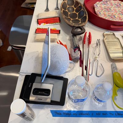 Sale Photo Thumbnail #123: Assorted kitchenware and electronics, including an Apple HomePod Mini, a Kindle e-reader, a Bose dock, and various utensils on a kitchen counter.