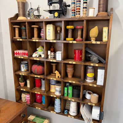 Sale Photo Thumbnail #44: Vintage wooden shadow box shelf filled with sewing notions, miniature Singer sewing machines, wooden spools, and various crafting supplies.