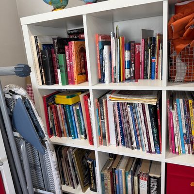 Sale Photo Thumbnail #33: White cube bookshelf filled with various books, craft supplies, and a collection of vintage globes displayed on top.