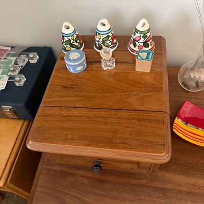 Sale Photo Thumbnail #14: Small wooden storage box with a single drawer, topped with three hand-painted ceramic bells, a blue Wedgwood jasperware trinket box, a small glass bottle, and a wooden alphabet block.