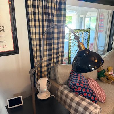 Sale Photo Thumbnail #207: Industrial-style adjustable metal floor lamp with a curved arm and a black dome shade, positioned next to a sofa.