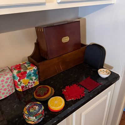 Sale Photo Thumbnail #24: Assorted household items including a wooden box, a wooden storage bin, colorful tissue box covers, and various decorative coasters on a dark countertop.