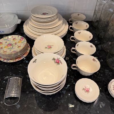 Sale Photo Thumbnail #137: Vintage floral china dinnerware set featuring delicate rose motifs, including plates, bowls, and teacups, displayed alongside a small metal hand grater.