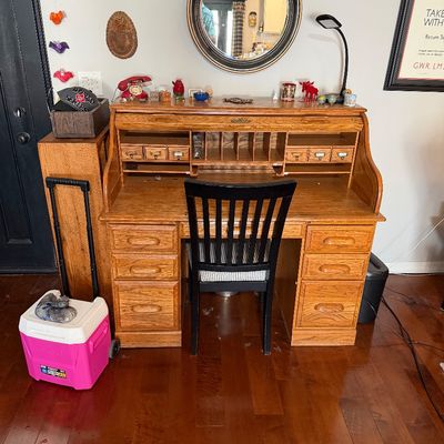 Sale Photo Thumbnail #210: Vintage oak rolltop desk with multiple drawers and cubbies, paired with a black wooden desk chair featuring a striped cushion.