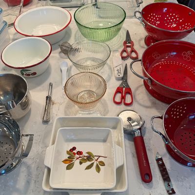 Sale Photo Thumbnail #132: Assortment of kitchenware including red enamel colanders, glass mixing bowls, baking dishes, and various utensils like scissors and a pizza cutter.